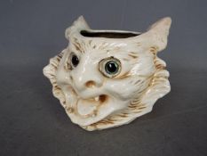 A Bretby Pottery grotesque cat head vase with applied glass eyes, approximately 12 cm (h).