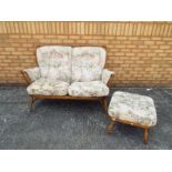 Ercol - A two seat sofa and footstool in Golden Dawn finish.