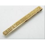 A 9ct gold tie clip with textured effect to the face, approximately 4 grams all in.