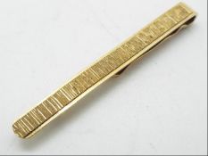 A 9ct gold tie clip with textured effect to the face, approximately 4 grams all in.