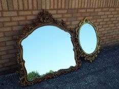 Two gilt framed oval mirrors, the larger one being approx 117 cm x 112 cm,