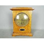 An Arts & Crafts style, golden oak cased mantel clock, engraved brass dial,