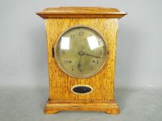 An Arts & Crafts style, golden oak cased mantel clock, engraved brass dial,