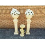 A matched pair of plant stands bearing urns with artificial floral displays,