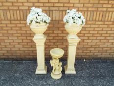 A matched pair of plant stands bearing urns with artificial floral displays,