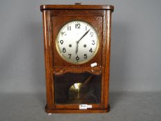 A HAC oak cased wall clock with key and pendulum.