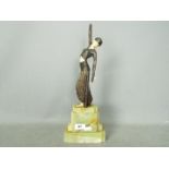 An Art Deco sculpture depicting a stylish lady in bronze with ivorine or bakelite face,