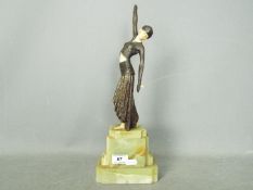 An Art Deco sculpture depicting a stylish lady in bronze with ivorine or bakelite face,