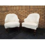 A pair of Victorian upholstered tub chairs raised on turned mahogany supports terminating in brass