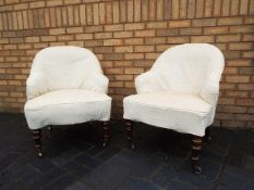 A pair of Victorian upholstered tub chairs raised on turned mahogany supports terminating in brass