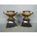 A pair of bronze urns raised on plinths (one plinth A/F), approximately 22 cm (h).