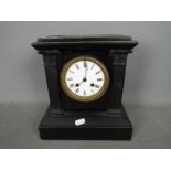 A black marble mantel clock of architectural form, Roman numerals to a white enamel dial,