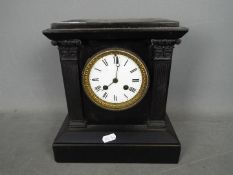 A black marble mantel clock of architectural form, Roman numerals to a white enamel dial,