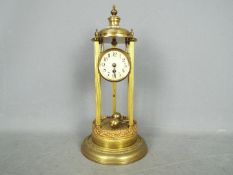 A torsion pendulum mantel clock in a brass and gilded bandstand or tholos style case,