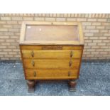 An oak fall front bureau with three graduated drawers, approximately 100 cm x 76 cm x 43 cm.