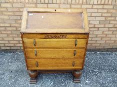 An oak fall front bureau with three graduated drawers, approximately 100 cm x 76 cm x 43 cm.