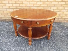 A circular topped coffee table on turned supports, approximately 51 cm x 89 cm.