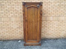 A single door oak wardrobe with carved detailing, approximately 184 cm x 78 cm x 40 cm.