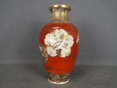 A large Japanese vase decorated with panels of samurai, scholars, flowers against a red ground,