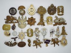 A quantity of military cap badges, a Silver War Badge (numbered 293324) and similar.