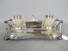 A plated desk tidy with two cut glass inkwells and recumbent greyhound figure to the centre.