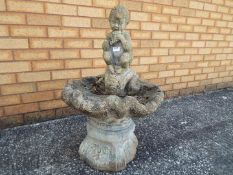 A reconstituted stone bird bath surmounted with pipe playing faun,