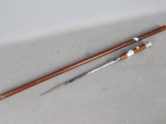 A early 20th century sword stick with short blade, white metal repousse top (presumed silver),