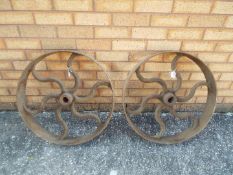 Two cast iron cart wheels or shaft drive wheels, approximately 60 cm (d).