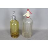 Two vintage soda syphons comprising a yellow Schweppes Limited Porcelain Lined Syphon and a