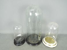 Three display domes and bases, largest approximately 49 cm (h).