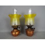 A set of two copper oil lamps with matching yellow glass shades, largest approximately 41 cm (h).