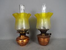 A set of two copper oil lamps with matching yellow glass shades, largest approximately 41 cm (h).