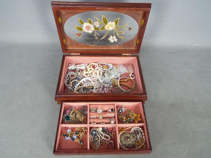 A jewellery box containing a quantity of costume jewellery including rings stamped 'Silver',