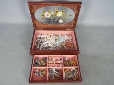 A jewellery box containing a quantity of costume jewellery including rings stamped 'Silver',