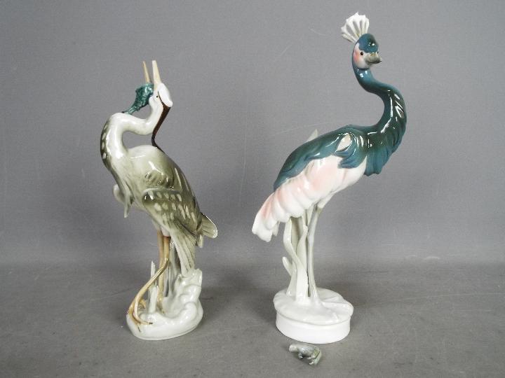 Royal Dux - Two bird figurines comprising a feeding heron and a peahen (one leg detached but