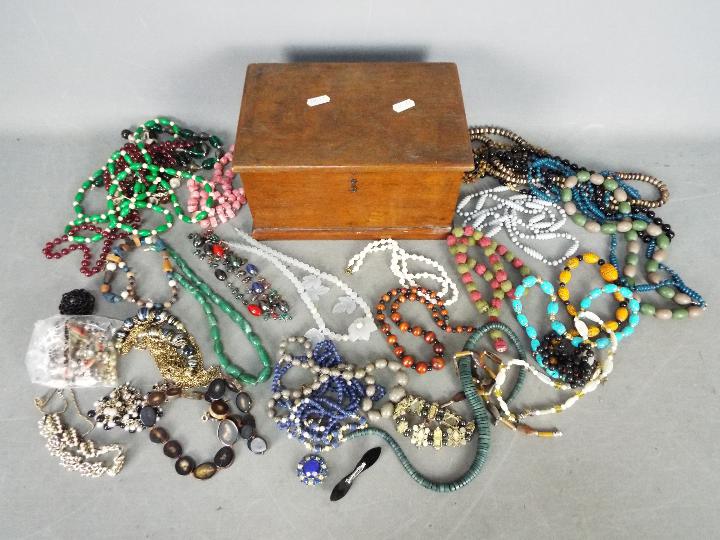 A wooden box containing a quantity of costume jewellery.