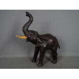 A vintage leather elephant with raised trunk, approximately 50 cm (h) to tip of trunk.