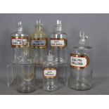 Six vintage clear glass pharmacy bottles, five with original labels, all with stoppers,