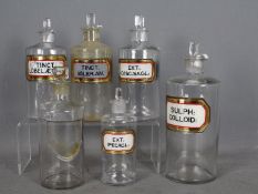 Six vintage clear glass pharmacy bottles, five with original labels, all with stoppers,