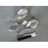 Three George V silver backed, dressing table pieces comprising two brushes and a comb,