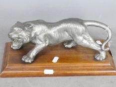 A cast metal model of a tiger, approximately 28 cm (l), mounted to wooden plinth.