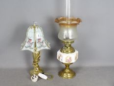 A brass oil lamp with ceramic reservoir, glass shade and chimney,