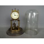 An early 20th century German torsion pendulum clock housed under glass dome,