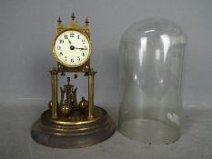 An early 20th century German torsion pendulum clock housed under glass dome,