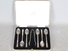 A George V cased set of silver coffee spoons comprising six spoons and sugar tongs,