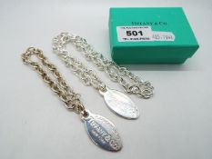 Two white metal oval tags and chains, the tags stamped Please Return To Tiffany & Co New York,