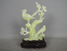 A Chinese, celadon green, bowenite carving of two perching birds, housed on wooden stand,