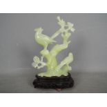 A Chinese, celadon green, bowenite carving of two perching birds, housed on wooden stand,