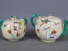 A Japanese teapot and sugar bowl with cover, hand painted decoration of birds in flight, signed.