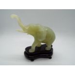 A Chinese, celadon green, bowenite carving of an elephant with raised trunk,